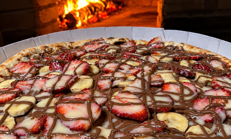 Pizza doce da Art Pura com morango, banana e chocolate, diante do forno aceso