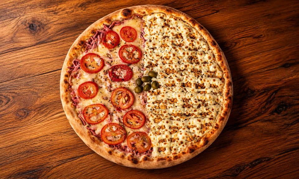 Pizza meio a meio da Art Pura vista de cima, uma metade com tomate e a outra com queijo